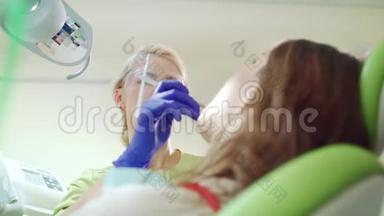 微笑牙医在牙科办公室和病人一起工作。 口腔专业